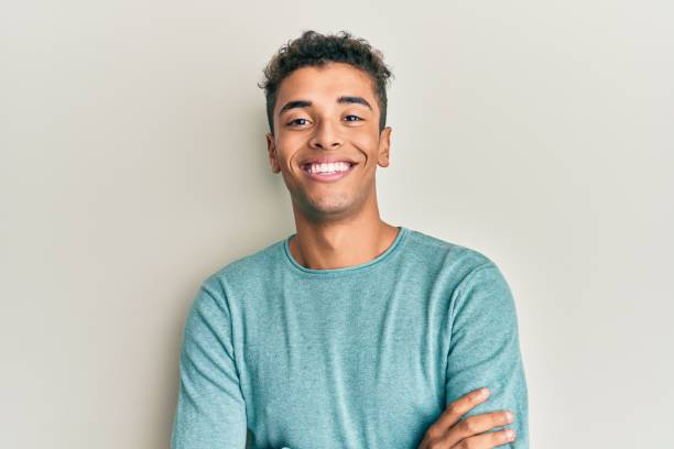 Young handsome african american man wearing casual clothes happy face smiling with crossed arms looking at the camera. positive person. stock photo