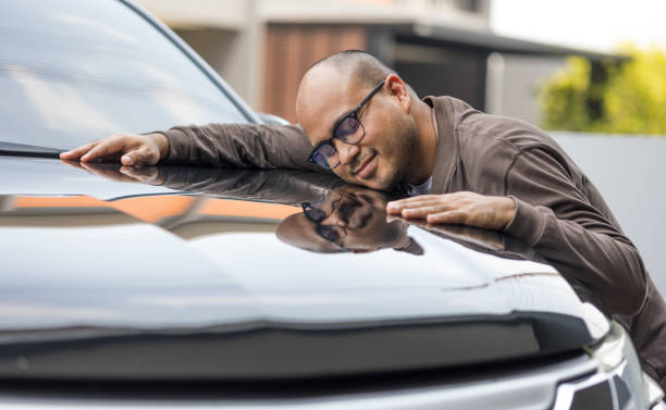 Young handsome asian man getting the new car. He hugged his car and was very happy. Buy or rent car concept. stock photo