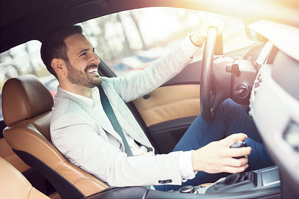 Young handsome businessman is driving a car Young handsome businessman is driving a car looking very happy. man driving suit stock pictures, royalty-free photos & images