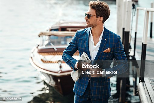 istock Young handsome man in classic suit over the lake background 1300966679