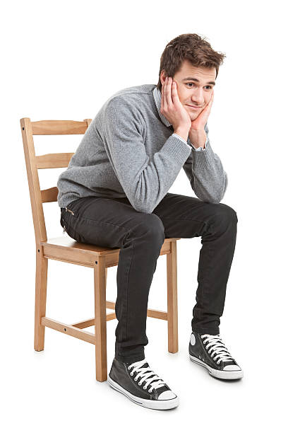 young handsome man in grey sweater sitting on chair stock photo