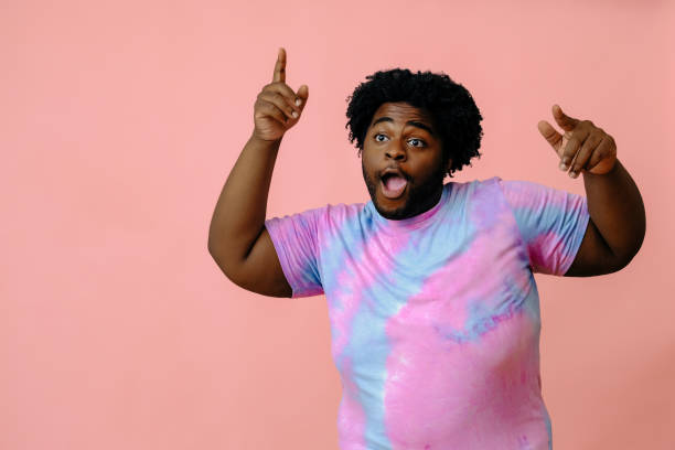 young happy african american man posing in the studio over pink background stock photo