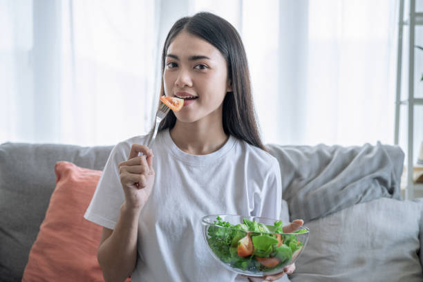 Young happy Asian woman eating healthy salad. stock photo