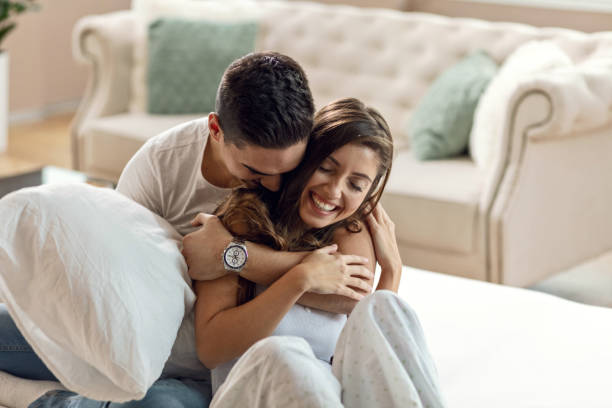 Young happy couple in love embracing in bedroom. Happy affectionate couple enjoying in their love while embracing in bedroom in the morning. falling in love stock pictures, royalty-free photos & images