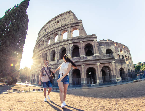 Young happy couple of tourist walking holding hands at Colosseum. Come with me. Rome, Italy Young happy couple of tourist walking holding hands at Colosseum. Come with me. Rome, Italy city break stock pictures, royalty-free photos & images