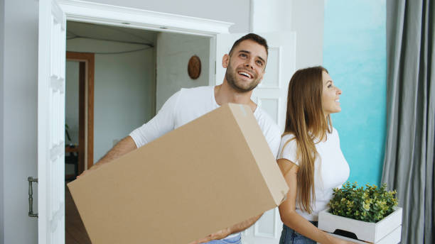 Young happy couple walking in new house after relocation stock photo
