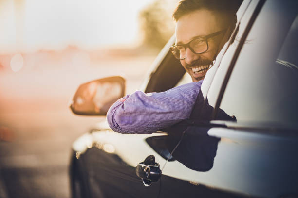 gelukkig jongeman besturen van een auto bij zonsondergang. - man with car stockfoto's en -beelden