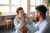 istock Young happy man with Down syndrome with his mentoring friend celebrating success indoors at school. 1347625803