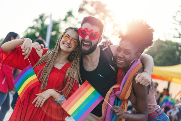 Young happy people meeting at the pride festival Excited young people at the pride event hugging, waving rainbow pride flags and having fun gay pride symbol stock pictures, royalty-free photos & images
