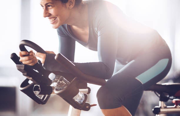 若い幸せなスポーツウーマンの回転のクラスを持つスポーツ ・ フィットネス センターでトレーニング。 - 自転車ジム ストックフォトと画像