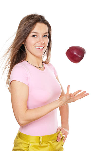 Young happy woman throwing apple stock photo