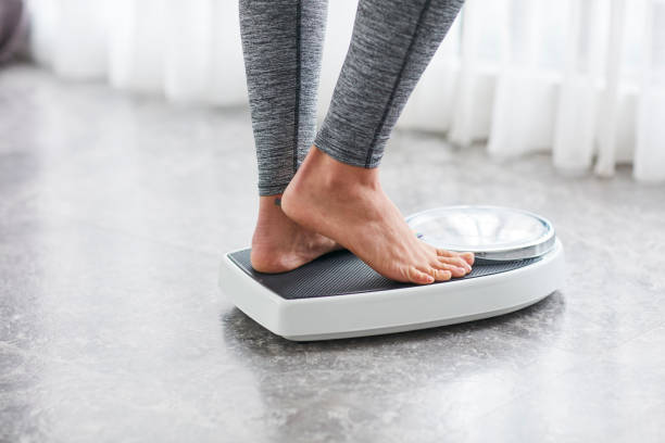 Young healthy girl on home scales stock photo