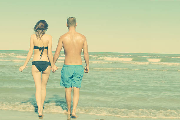 young hipster couple walk on a lonely beach stock photo