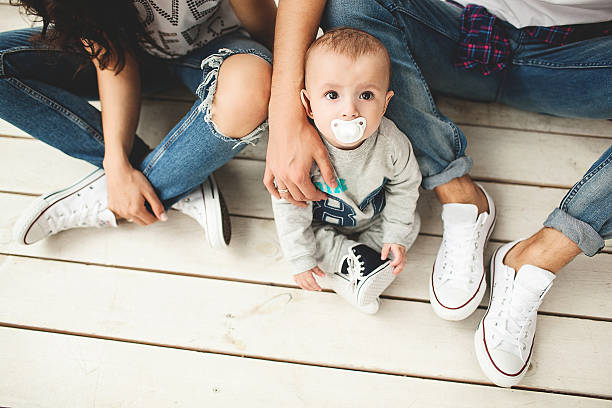 Young hipster father, mother and baby boy on wooden floor stock photo
