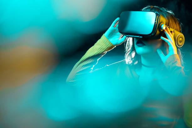 Young hipster woman with curly hair wearing virtual reality goggles and touch another world in studio neon lights. Smartphone using with VR headset. Young hipster woman with curly hair wearing virtual reality goggles and touch another world in studio neon lights. Smartphone using with VR headset vr stock pictures, royalty-free photos & images