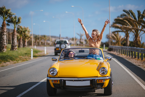 Young Hipster Women Driving Vintage Convertible Car On Road Trip Stock