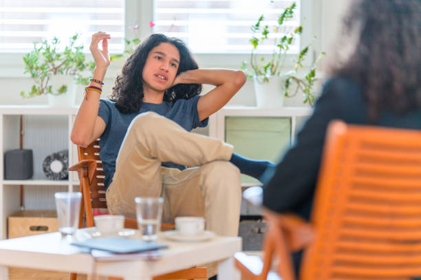 Young Hispanic Male Patient Listening To Female Psychotherapist in her Office stock photo
