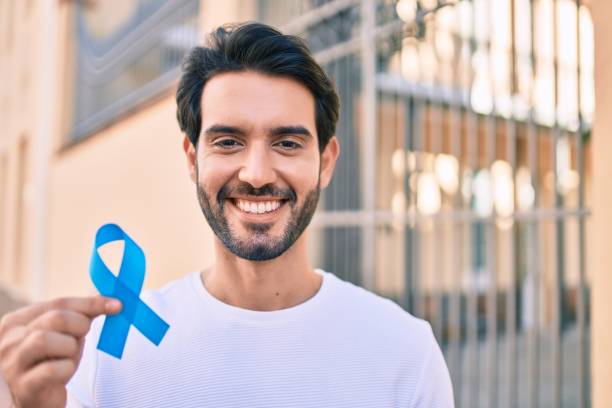 Young hispanic man smiling happy holding blue ribbon at the city. stock photo