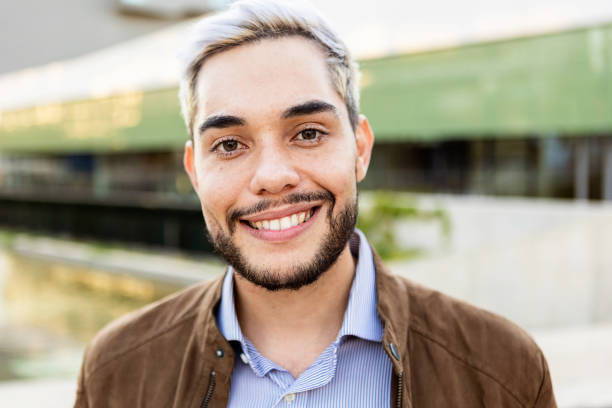 Young hispanic man smiling on camera outdoors stock photo