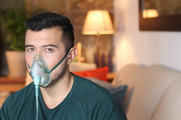 Jonge Spaanse mens die zuurstofmasker gebruikt​​​ foto