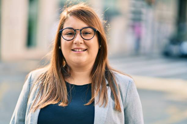Young hispanic plus size businesswoman smiling happy standing at the city. stock photo