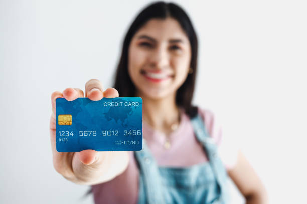 Young hispanic woman holding blue credit card isolated over white background in Latin America stock photo