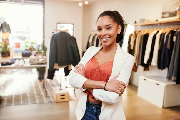 Young Hispanic woman smiling to camera in a clothes shop Young Hispanic woman smiling to camera in a clothes shop assistant stock pictures, royalty-free photos & images