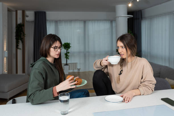 Young homeowner woman sitting at home with a young female student who wants to rent an cozy apartment to live in while she is studying in college and discussing price terms and obligations stock photo