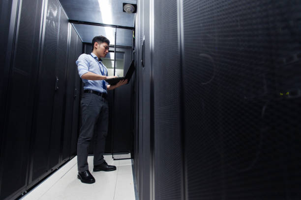 Young IT engineer inspecting data center servers stock photo