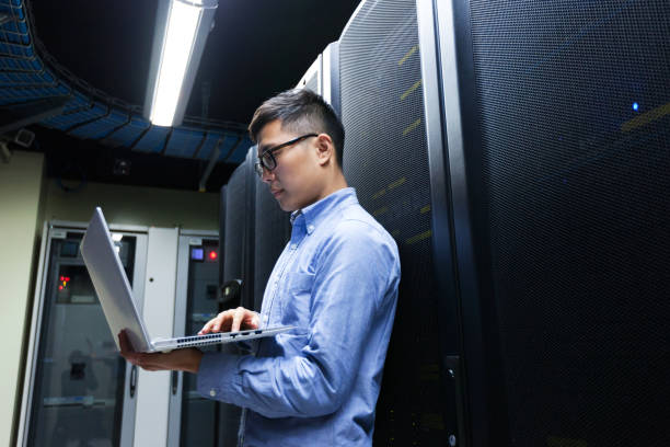 Young IT engineer inspecting data center servers stock photo