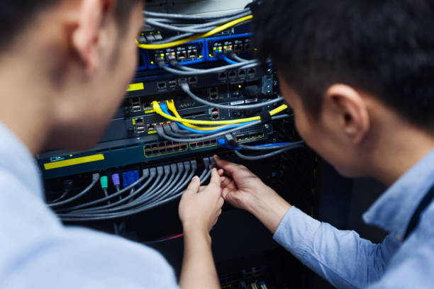 Young IT engineer inspecting network cable stock photo