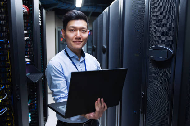 Young IT engineer standing near data center servers stock photo