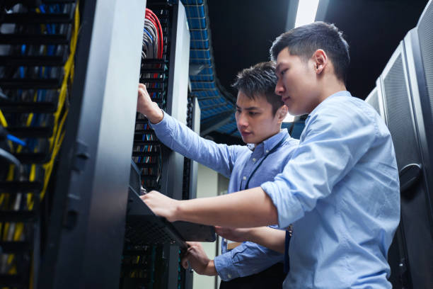 Young IT engineers inspecting data center servers stock photo