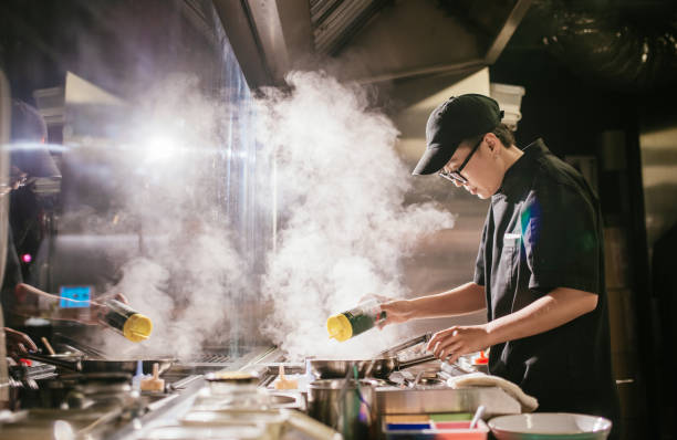 junger japanischer koch arbeitet in derinsenküche - asiatischer koch stock-fotos und bilder