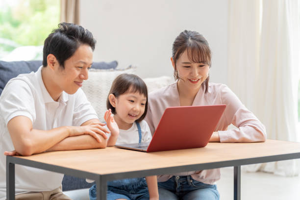 リビングルームでラップトップを使用して若い日本の家族 - 親子 ストックフォトと画像