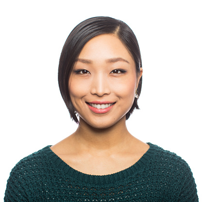 Portrait of young asian woman looking confident against white background. Close-up of Japanese female with short hair looking at camera and smiling.