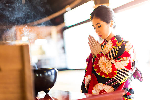 Young Japanese Woman Praying at Hyakumanben Chionji Temple, Kyoto, Japan A young Japanese woman in traditional Kimono praying at Hyakumanben Chionji Temple, Kyoto, Japan shy japanese woman stock pictures, royalty-free photos & images