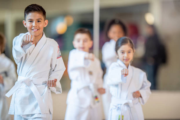 Young karate class A diverse group of young children practice karate in a class setting. karate stock pictures, royalty-free photos & images