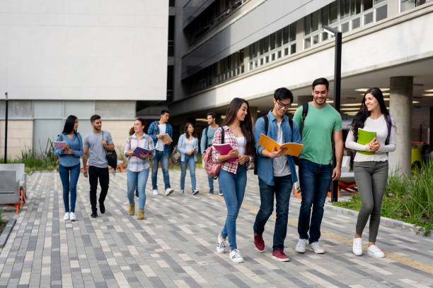 jóvenes estudiantes latinoamericanos que abandonan el campus universitario después de un día de clase - college campus fotografías e imágenes de stock