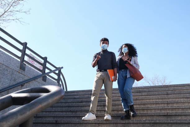jong latijns paar dat beschermend gezichtsmasker draagt dat onderaan het station loopt. nieuw normaal op de universiteitscampus. - europe city map stockfoto's en -beelden