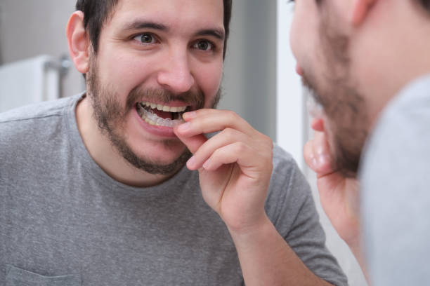 Young latin man wearing orthodontic silicone trainer or invisible braces aligner. Mobile orthodontic appliance for dental correction. stock photo