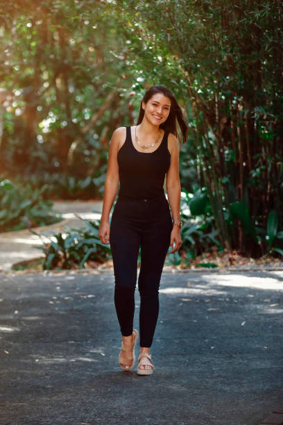 young Latina woman dressed in black jeans and tank top walking in a park in Costa Rica stock photo