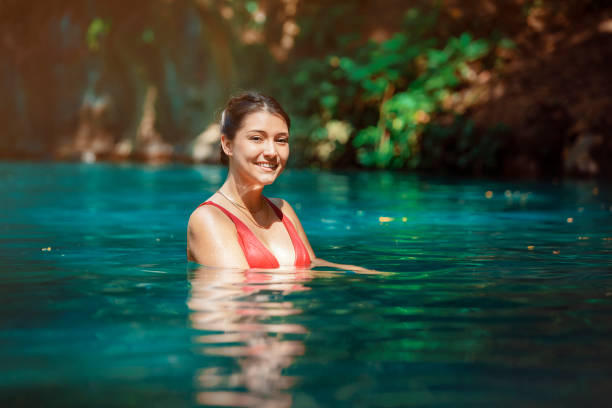 young Latina woman standing in blue green waters of Rio Blanco in Costa Rica stock photo
