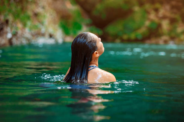 young Latina woman swimming in Rio Fortuna in Costa Rica with totally wet long hair stock photo