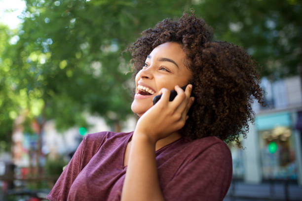 young laughing african american woman talking with cellphone outdoors stock photo