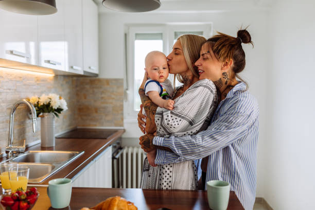 Young LGBT family spending time together Same sex couple in pajamas hold their baby son and enjoying time spent together at home child lover stock pictures, royalty-free photos & images