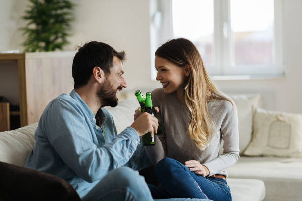 Young loving couple toasting with beer at home stock photo