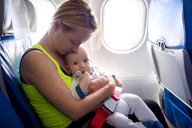 Young loving mother and her baby traveling by airplane. stock photo