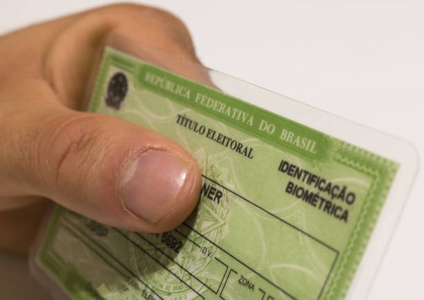 Young male hand holding brazilian elector's title. (translation: "Federative Republic of Brazil, voter title). stock photo