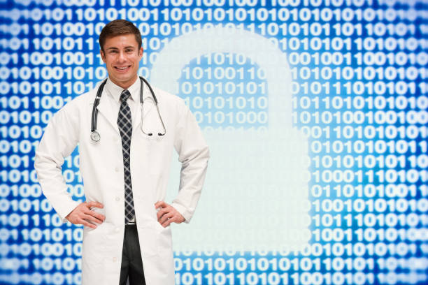 Young male technician wearing lab coat and using computer stock photo
